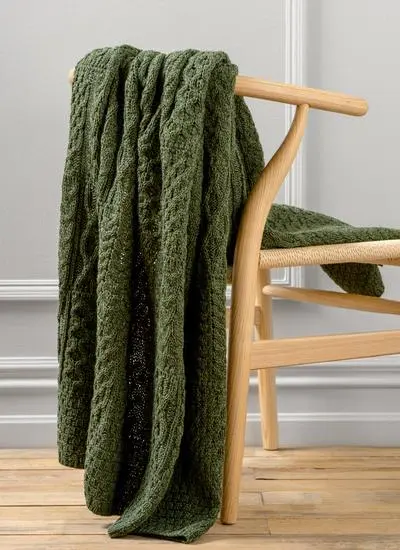 Dark green Aran throw draped across wooden chair